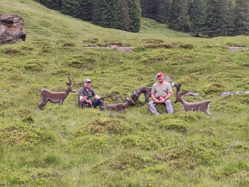 Bogenschütze spannt Jagdbogen auf grünem 3D-Parcours im Raurisertal vor Bergkulisse