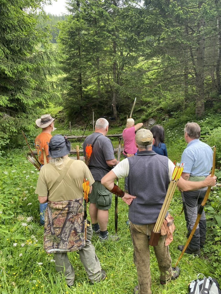 Bogenschütze spannt Jagdbogen auf grünem 3D-Parcours im Raurisertal vor Bergkulisse