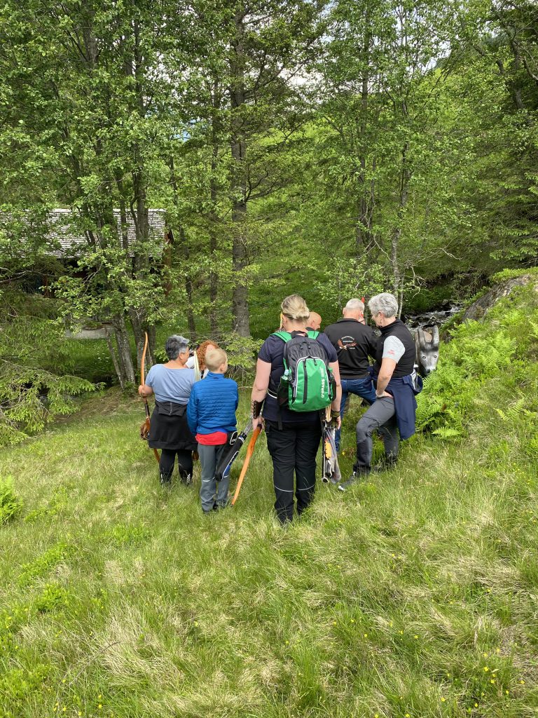 Bogenschütze spannt Jagdbogen auf grünem 3D-Parcours im Raurisertal vor Bergkulisse