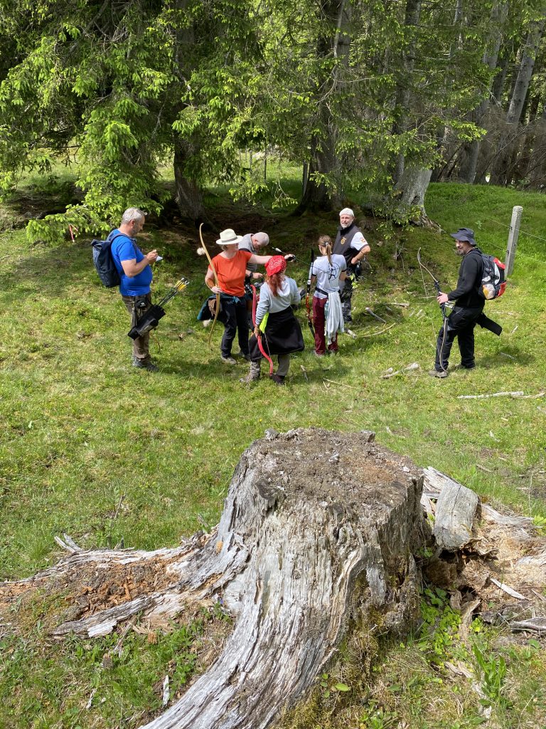 Bogenschütze zielt mit Jagdbogen im grünen Raurisertal, umgeben von Natur und Parcourszielen
