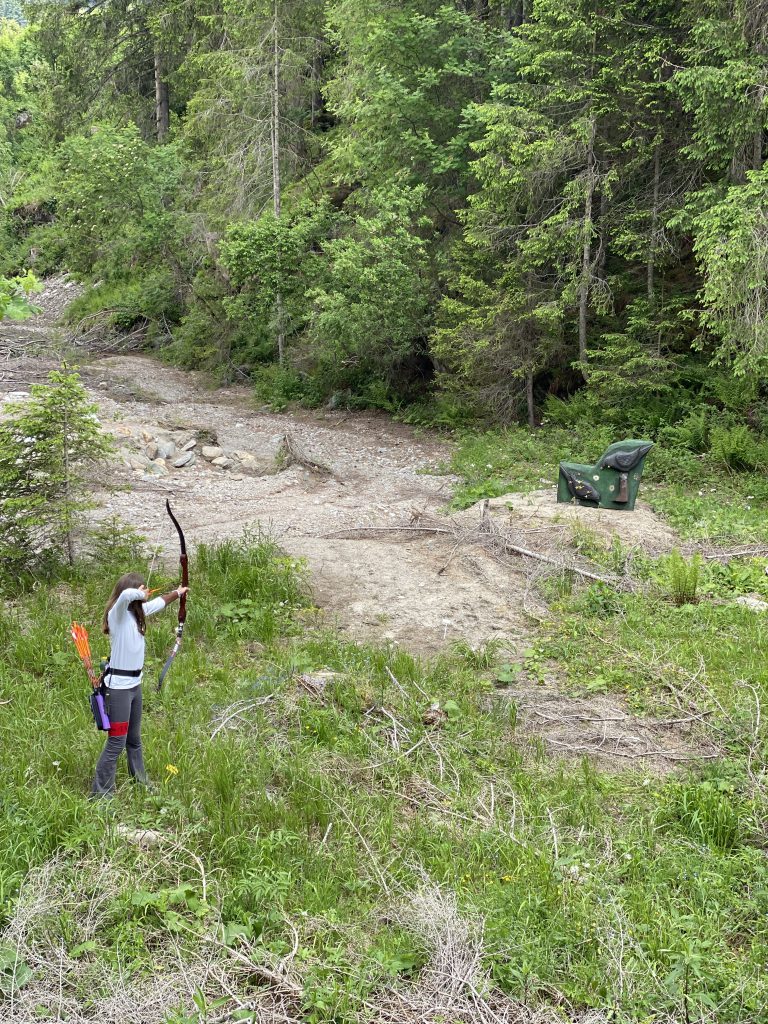 Bogenschütze spannt Jagdbogen auf grünem 3D-Parcours im Raurisertal vor Bergkulisse