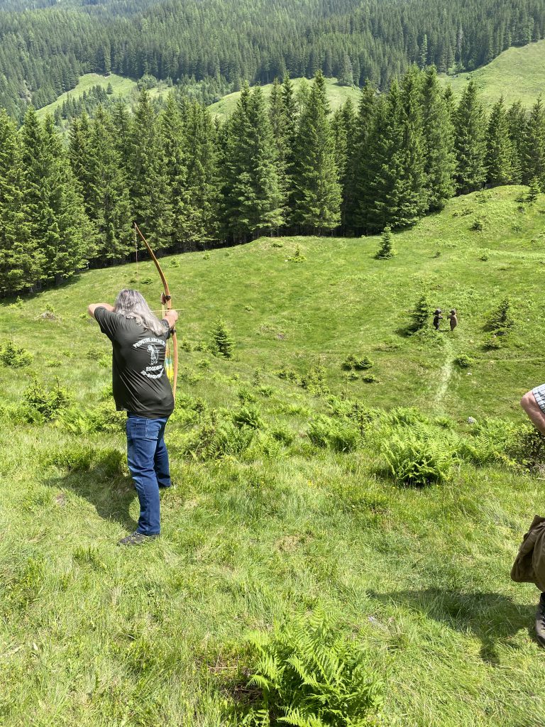 Bogenschütze spannt Jagdbogen auf grünem 3D-Parcours im Raurisertal vor Bergkulisse