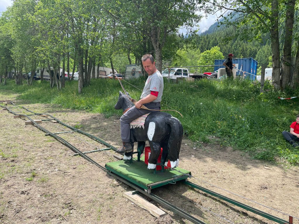 Bogenschütze spannt Jagdbogen auf grünem 3D-Parcours im Raurisertal vor Bergkulisse