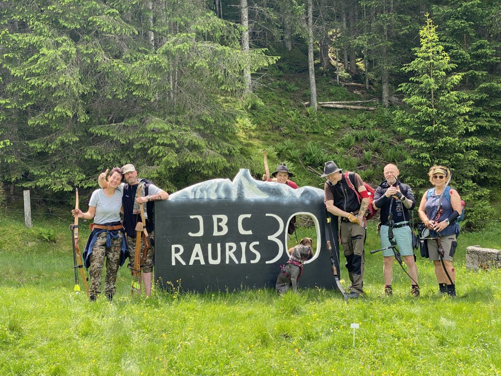 Bogenschütze spannt Jagdbogen auf grünem 3D-Parcours im Raurisertal vor Bergkulisse