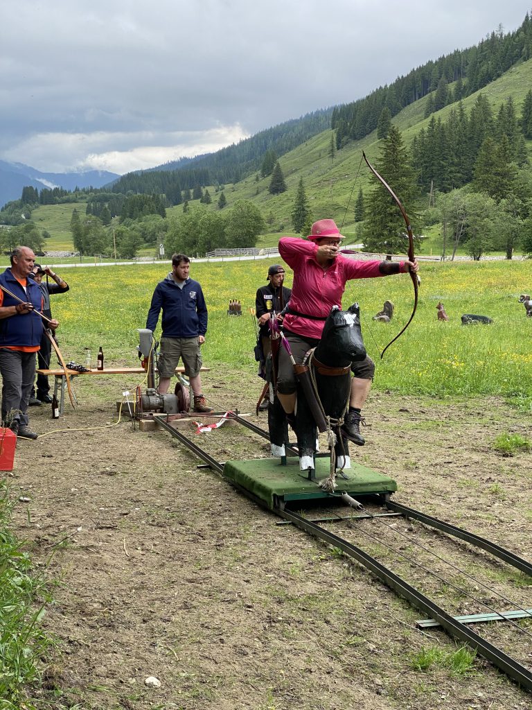 Bogenschütze spannt Jagdbogen auf grünem 3D-Parcours im Raurisertal vor Bergkulisse