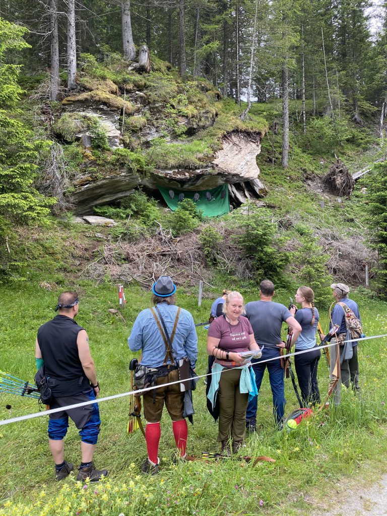 Bogenschütze zielt mit Jagdbogen auf 3D-Ziel im grünen Parcours des Raurisertals