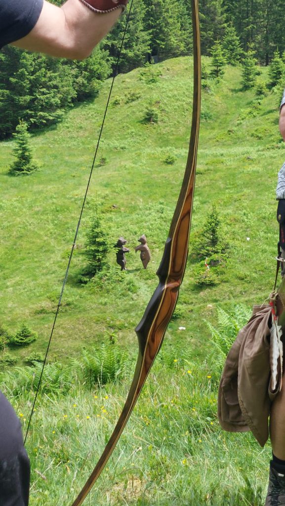 Bogenschütze spannt Jagdbogen auf grünem 3D-Parcours im Raurisertal vor Bergkulisse