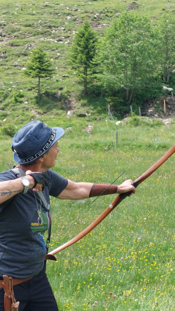 Bogenschütze spannt Jagdbogen auf grünem 3D-Parcours im Raurisertal vor Bergkulisse